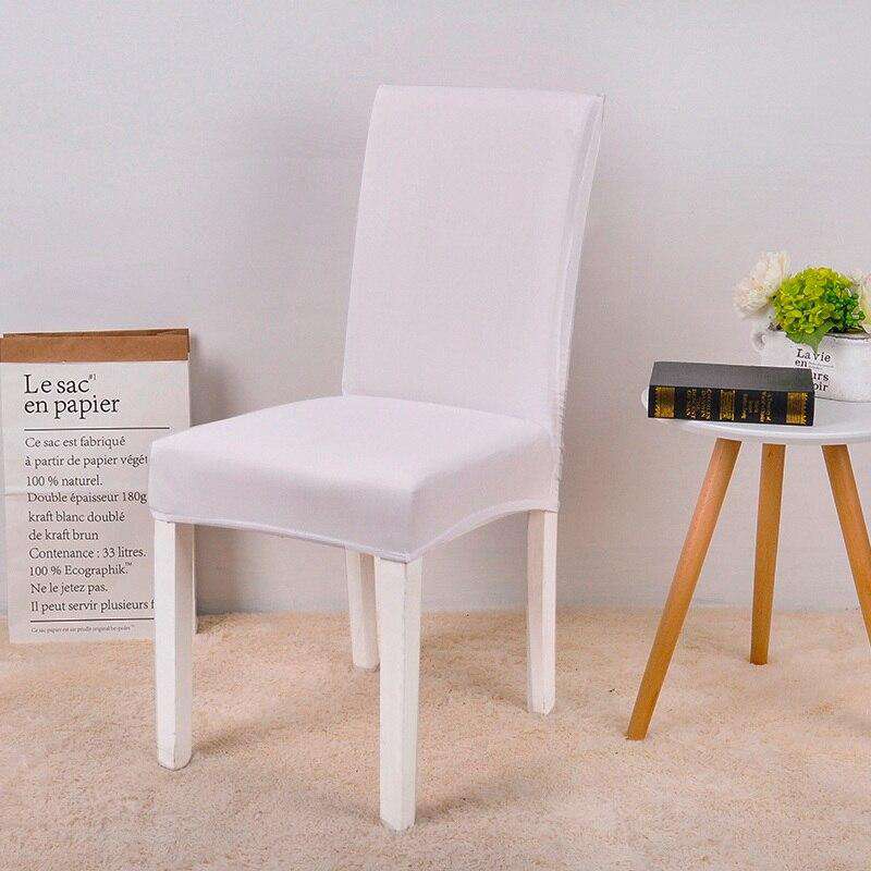Funda de silla blanca universal en una silla de comedor moderna, con decoraci??n de una mesa lateral y flores, ideal para ventas en tiendas online de cubiertas para muebles en blueemoonco.com