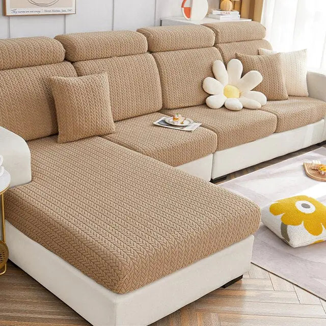 Fundas de sof?­ de color beige con textura trenzada en un sof?­ seccional moderno, decorado con cojines y una flor decorativa grande, perfectas para renovar y proteger tus muebles. Disponible en blueemoonco.com, tienda especializada en fundas para sof?­s y sillas en la UE y Espa?ña.